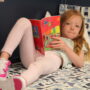 Kindergarten child reads a book in her classroom