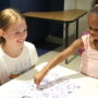 A middle school CIT helps a kindergartner during an art activity